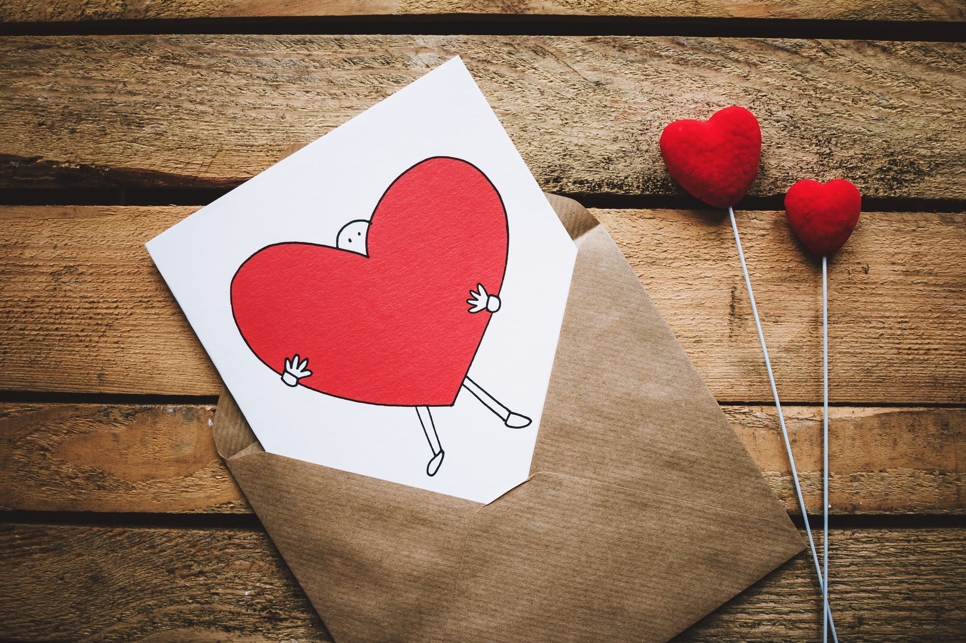 white black and red person carrying heart illustration in brown envelope